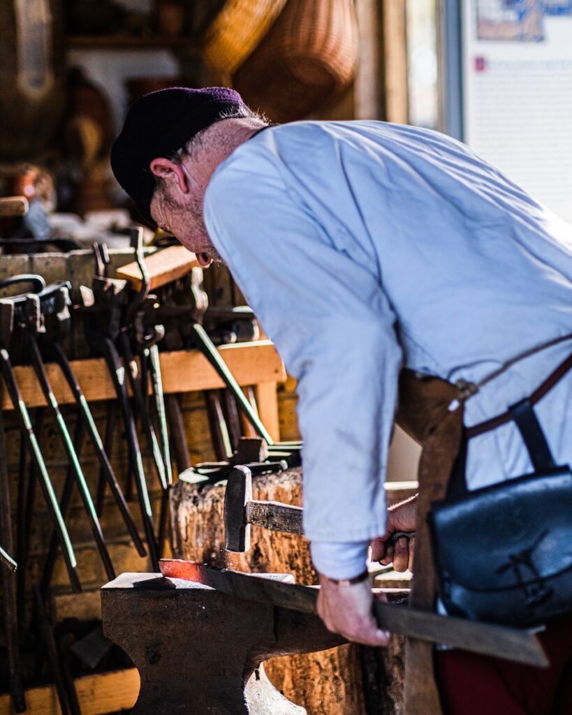 a man in a white shirt and red pants working on a piece of wood