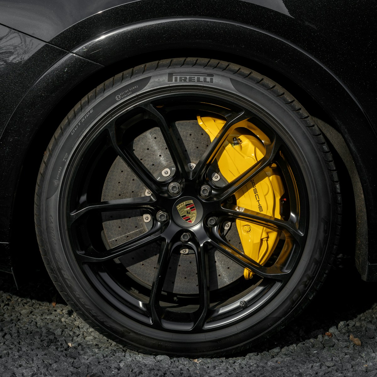 A black car wheel with yellow brake calipers.
