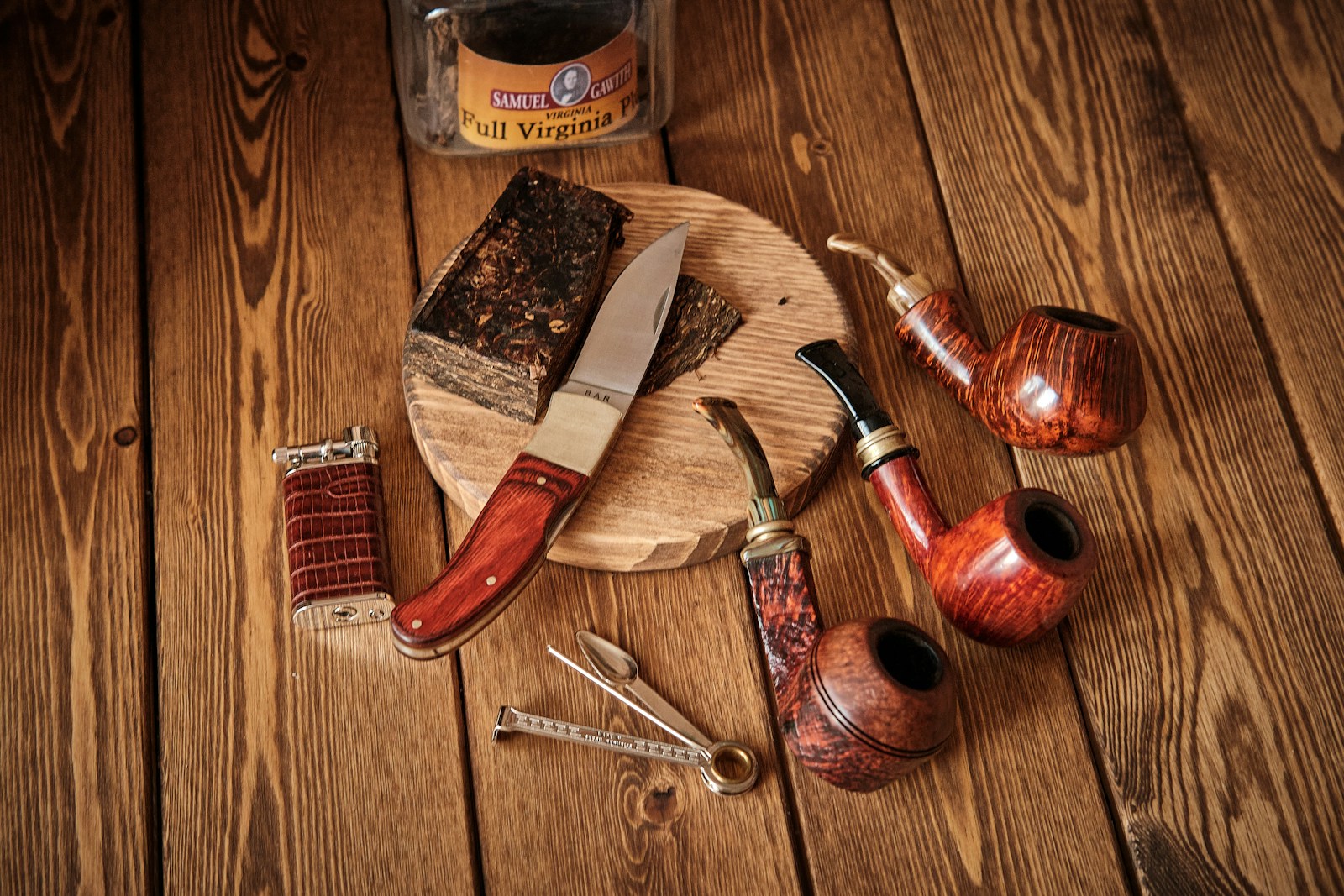 red and silver hand tool beside brown handle knife